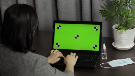 Woman-are-typing-on-laptop-keyboard-with-green-screen,-chroma-key.-Distance-work