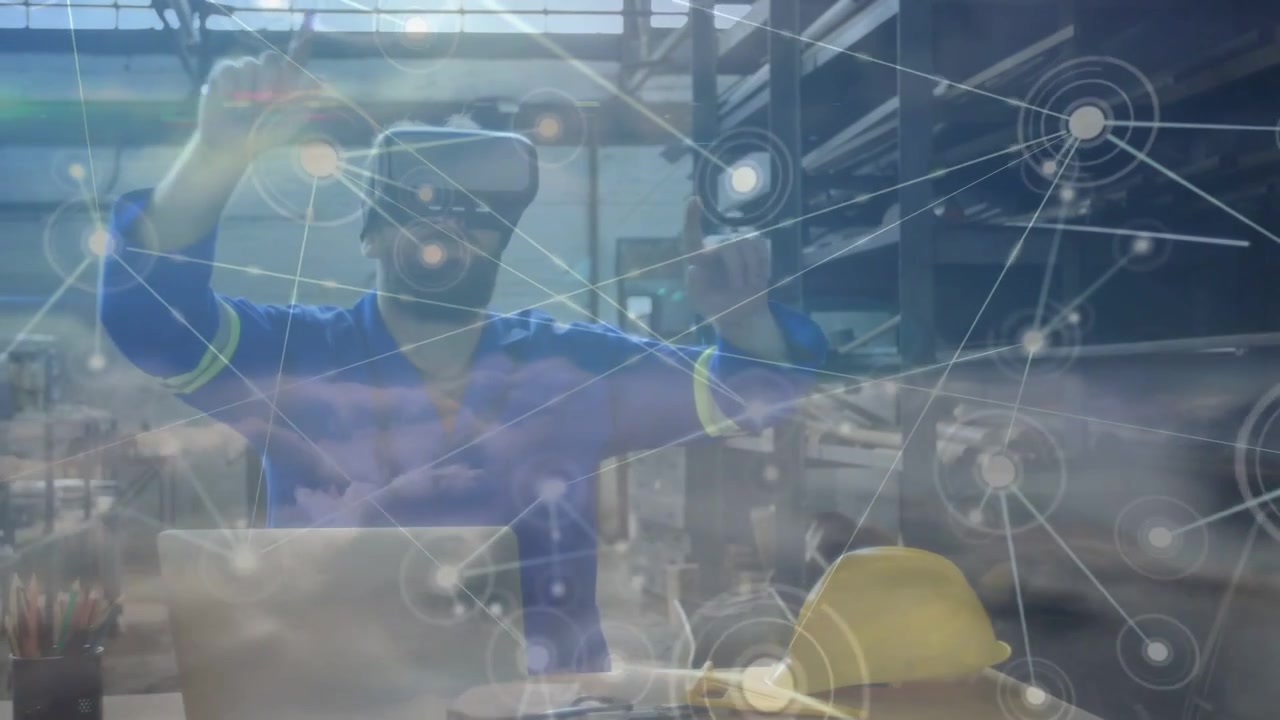 Man wearing VR headset at desk, touching laptop then moving network overlay for industrial layout