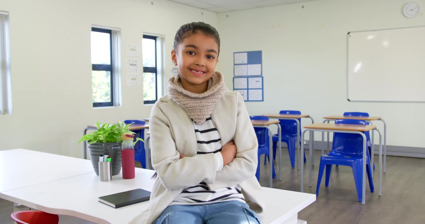 Adolescente afroamericano seduto sul tavolo della classe, dopo un segnale fuori campo si gira e sorride con una bottiglia rossa.