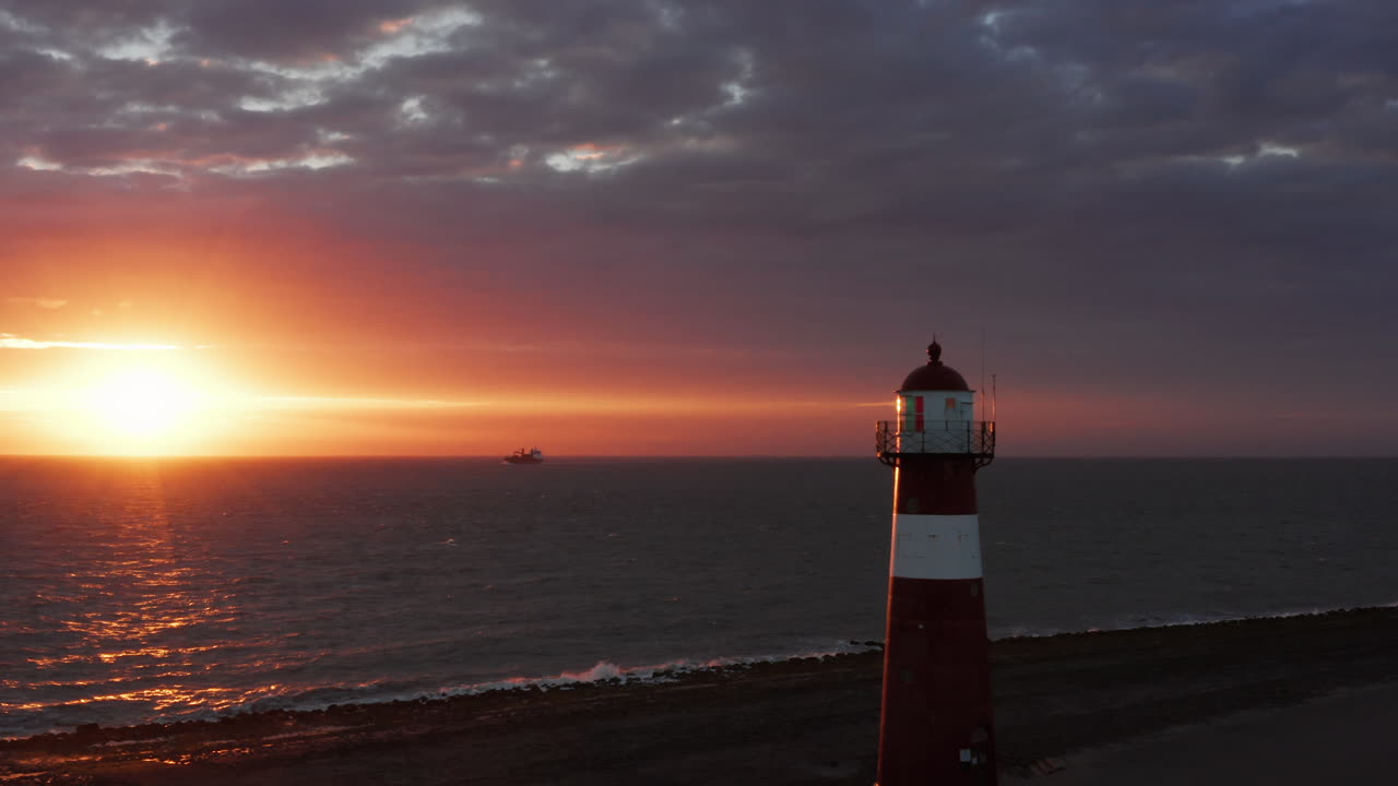 The lighthouse of Westkapelle during a bright orange sunset, with a lot of wind
