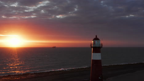 el faro de westkapelle durante una puesta de sol naranja brillante, con mucho viento