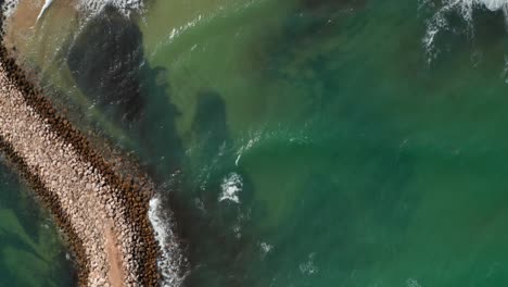 aerial birds eye overhead top down view of breakwater barrier in lagos, portugal, drone flying forward reveals beautiful sandy beach coastline, day