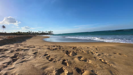 Olas-Del-Océano-Rodando-Sobre-Una-Playa-De-Arena-Con-Palmeras-En-El-Horizonte-Lejano-En-Punta-Cana,-Dominicana