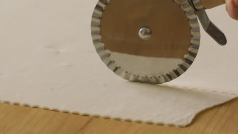 cutting strips of dough with fluted pastry wheel cutter