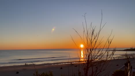 wide shot revealing an huge sunset in the middle of cliffs at sunrise on carcavelos beach