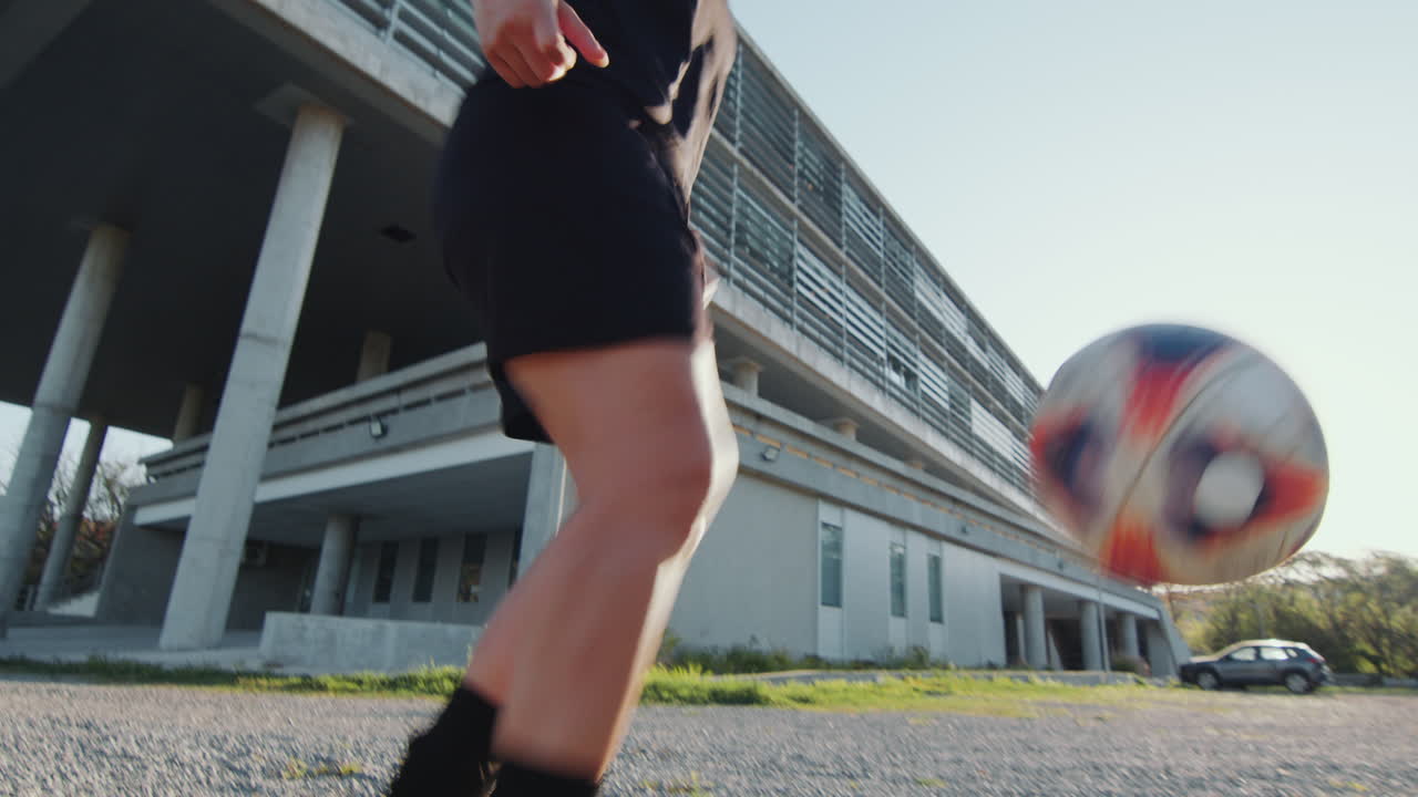 路上でサッカーボールでキックアップを練習している女性アスリート