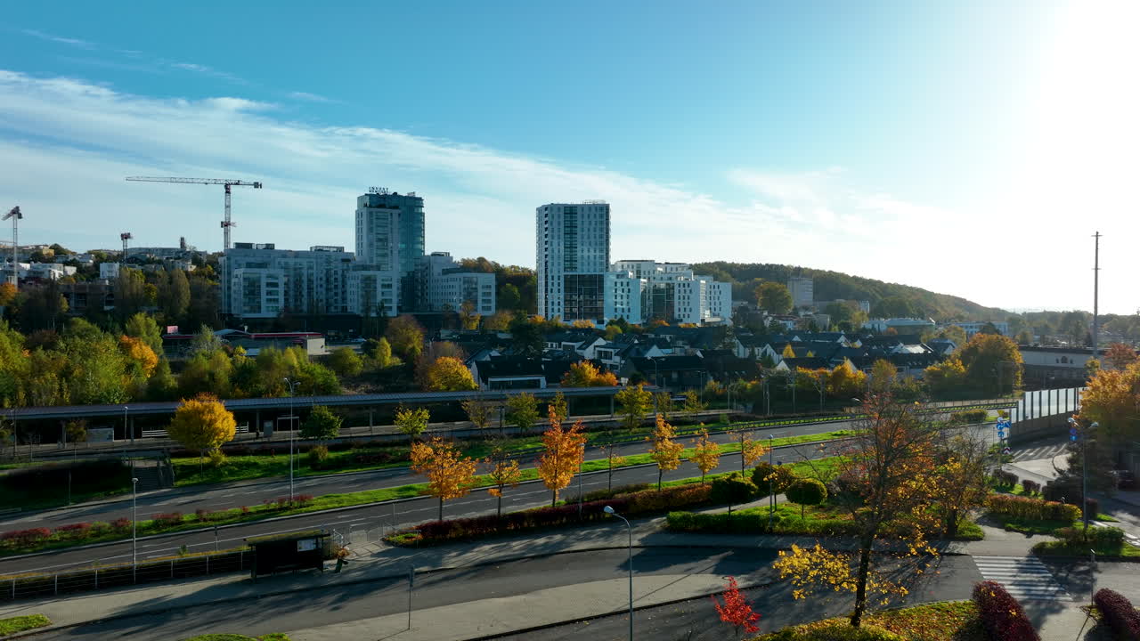 Modern residential and business buildings in Gdynia seen from park with autumn trees and blue sky