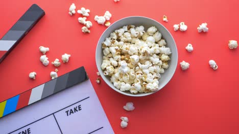 popcorn and clapperboard on red background