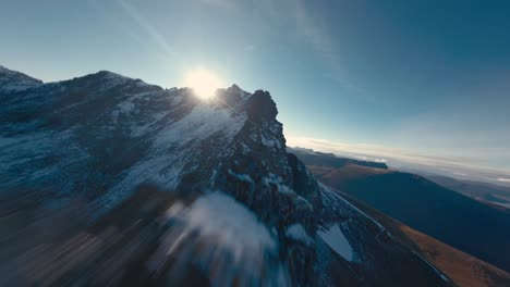 fpv flight over rocky and snowy mountain peaks during sunny day in norway in winter