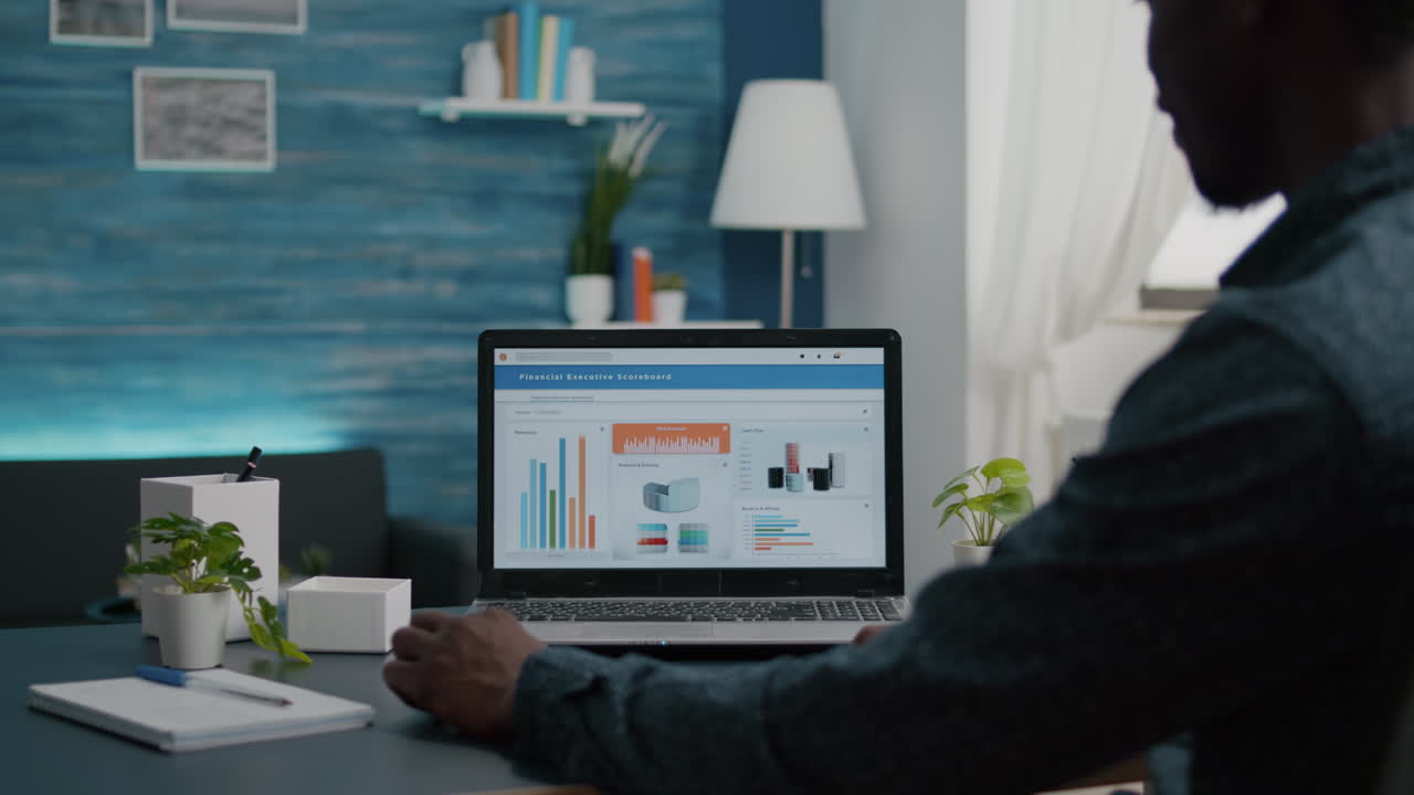 Black man working from home, remote working from living room using financial economy data app