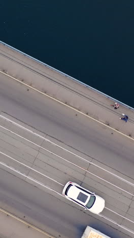 aerial view. two-way traffic on the bridge over the river. close-up of city traffic. vertical video