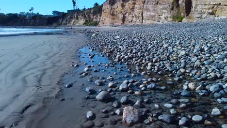 Volando-Bajo-Al-Suelo-Sobre-Rocas-Y-Agua-En-La-Playa