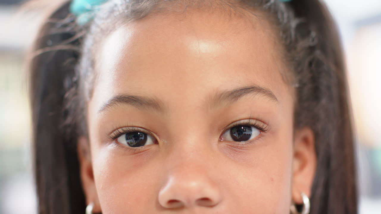 Close-up of girl with pigtails in school, looking directly at camera