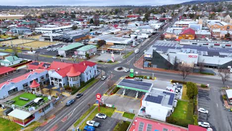 drone camera smoothly flies above a suburban roundabout in armidale, new south wales, capturing roads, buildings, and light traffic under overcast daylight