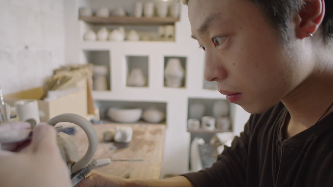 Young Asian Potter Working on Ceramic Mug