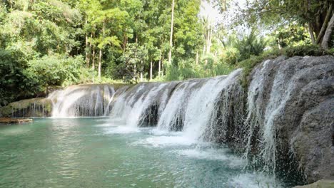 tripod shot of water flowing from cambugahay falls into natural turquoise pool in siquijor island, the philippines in ultra slow motion