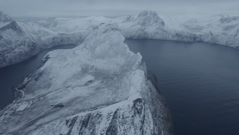 Vista-Aérea-Sobre-La-Montaña-Nevada-De-Segla,-Invierno-En-Senja,-Noruega---Reversa,-Disparo-De-Drones