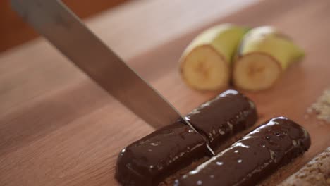 cutting oatmeal bar in half, covered in chocolate, slow motion close up