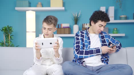 Two-friends-playing-games-with-phone-and-tablet.