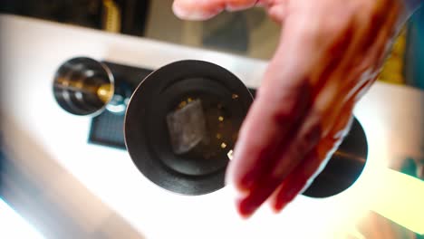 fotografía cenital de las manos de un camarero llenando una coctelera con hielo usando una cuchara para hielo