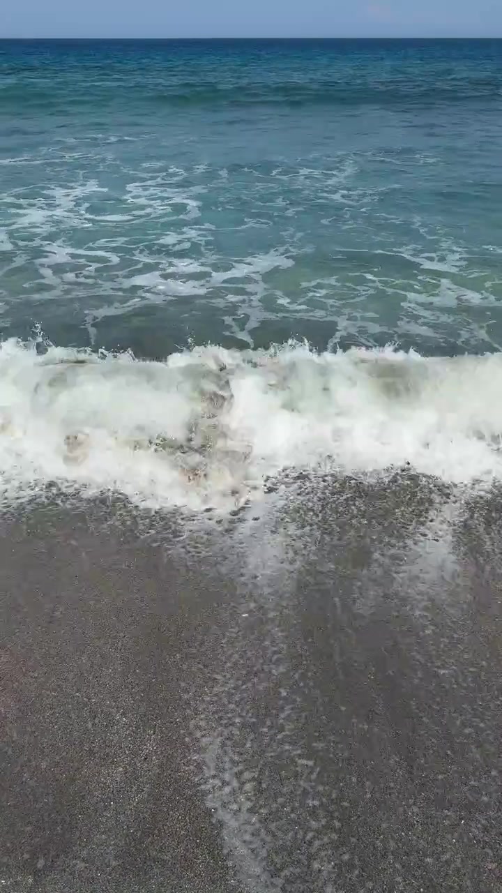 Onde delicate che si infrangono su una spiaggia di sabbia scura