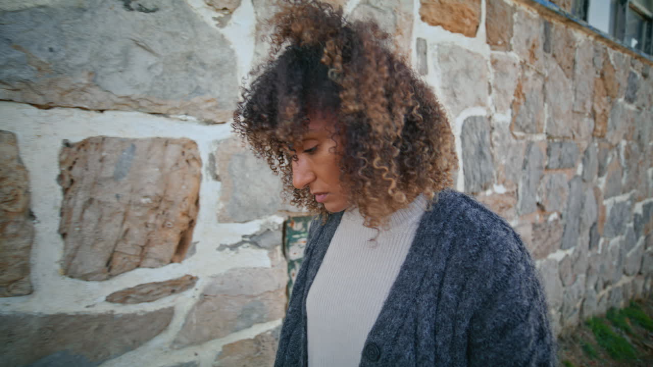 Upset lady strolling castle rocky wall closeup. Brunette feeling frustrated