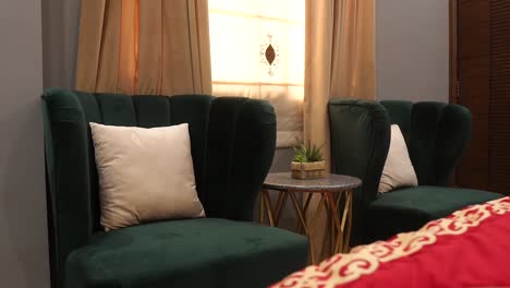 shot of a dark green sofas on both sides of a table with the view of a window in the background in a living room interior