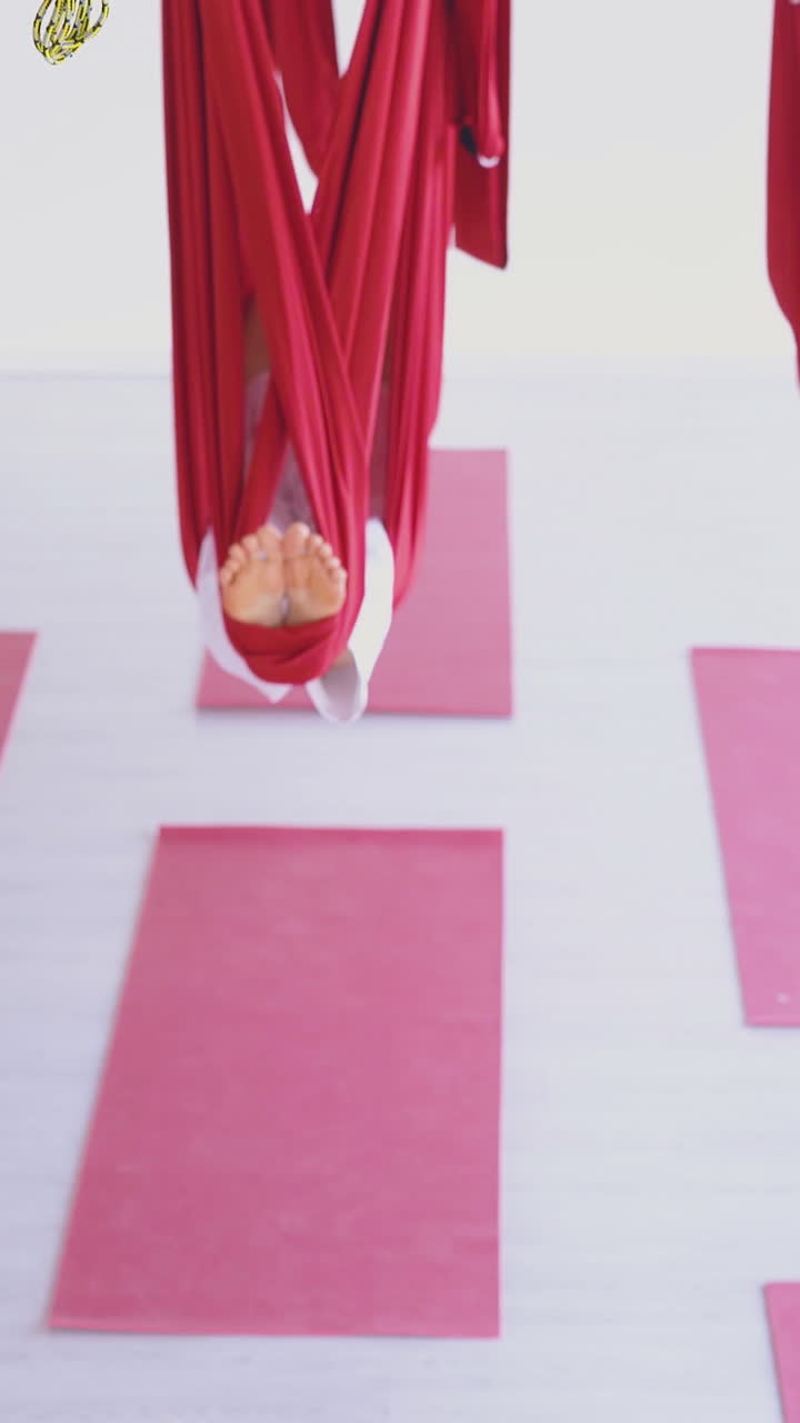women group lies relaxed in special bright red hammocks after aerial fly yoga in modern fitness classroom close view