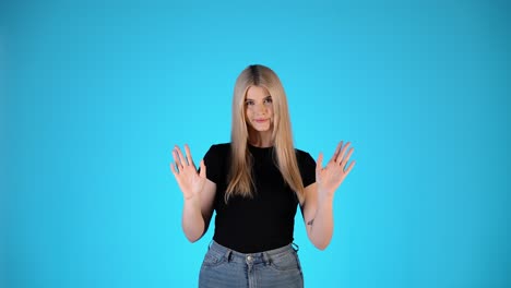 portrait of young blonde woman waving both hands, greeting hello gesture, colorful studio shot