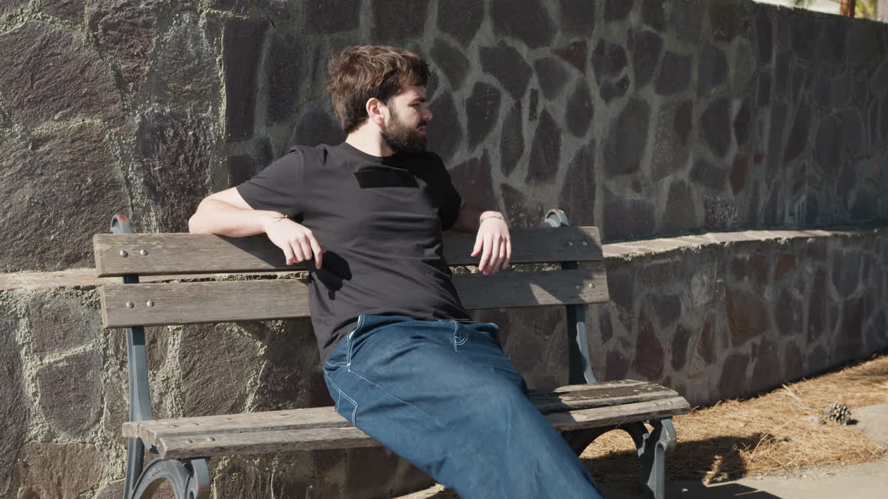 Young Man Relaxes On The Bench As The Wind Blows