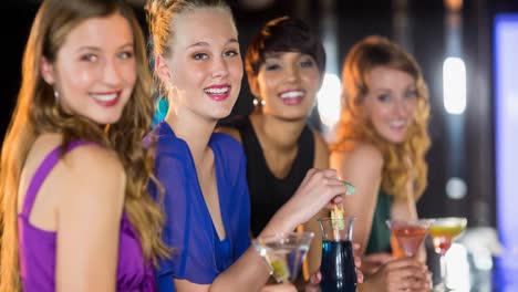 Happy-diverse-female-friends-smiling-and-enjoying-drinks-at-bar