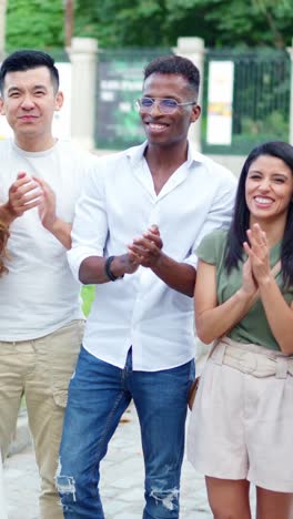 diverse group of people clapping and smiling outdoors