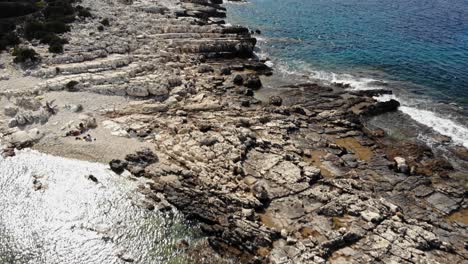 aerial view of rocky shore at paralia emplisi beach in greece during summer - drone shot