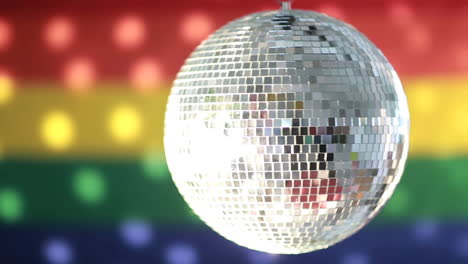 bola de discoteca girando contra la bandera del arco iris