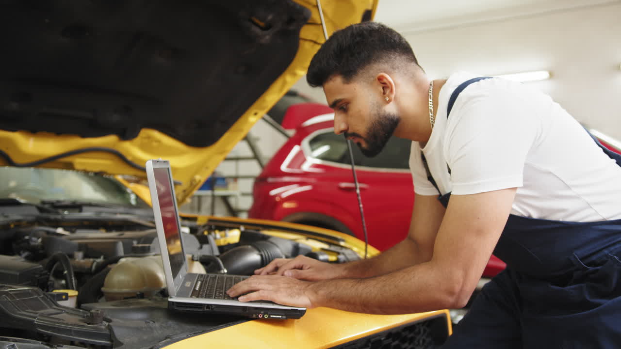 mecánico trabajando en un coche con una computadora portátil