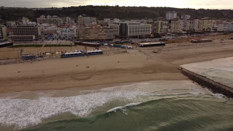 Costa-da-Caparica-Beach-during-sunrise-sunbeams,-Aerial-Pullback-shot