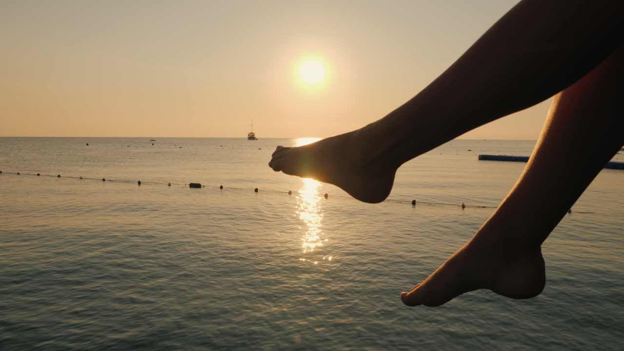 la mujer charla descuidadamente con los pies sobre el fondo del mar y el sol naciente en el dist