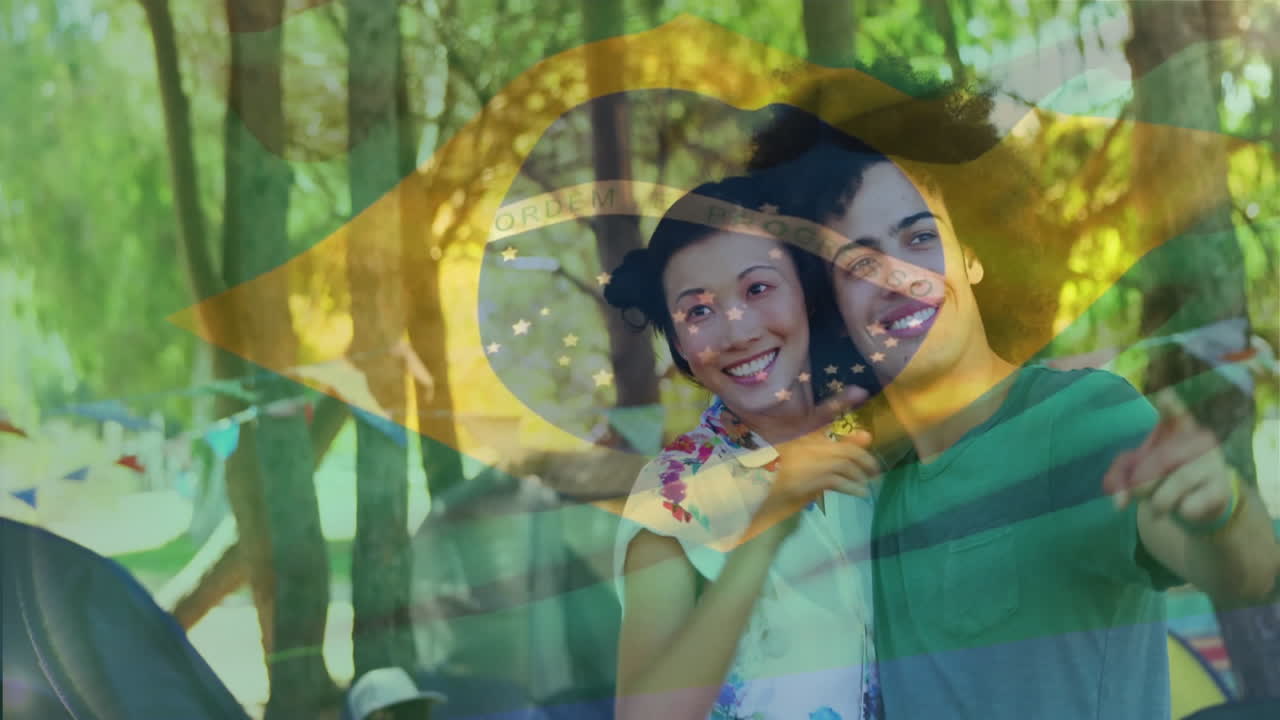 Aproveitando o ar livre, casal sorridente com animação da bandeira brasileira ao fundo