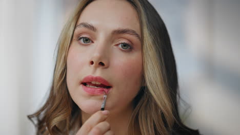 woman applying lipstick with a lip brush