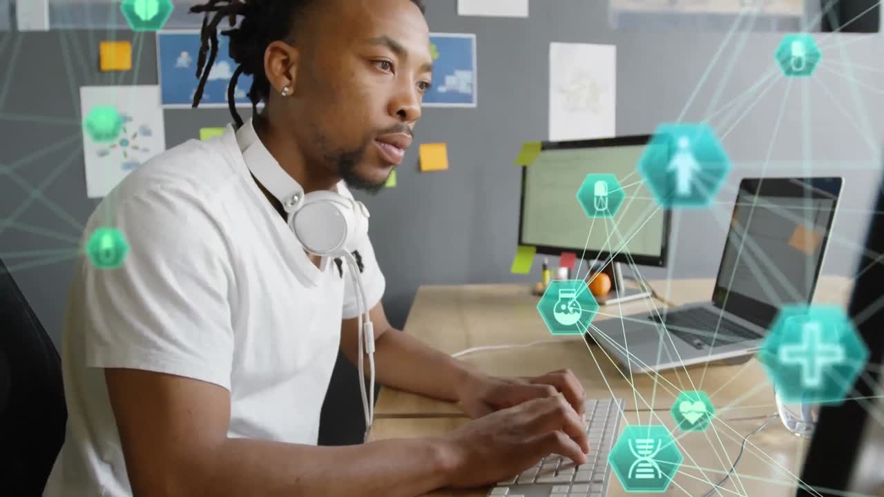 Animation of globe of digital icons against african american man using computer at office