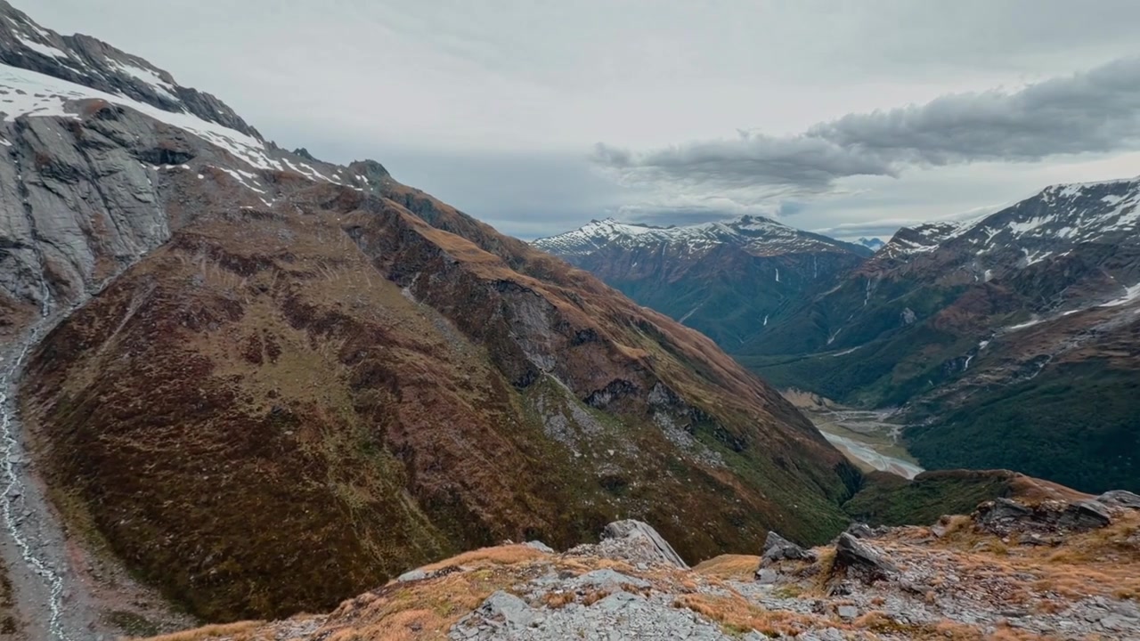 Spectacular alpine landscape featuring snow-covered peaks, rugged rock faces, and steep mountain ridges in New Zealand's Southern Alps. Scenic wilderness footage perfect for travel and nature projects