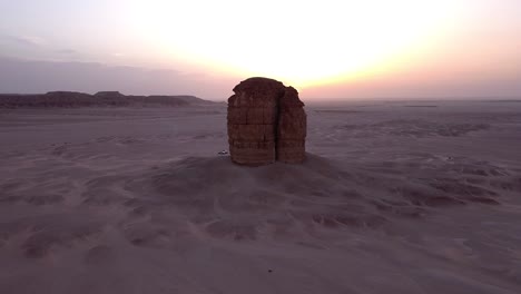 lonely sandstone cliff in middle of desert in aerial orbit view