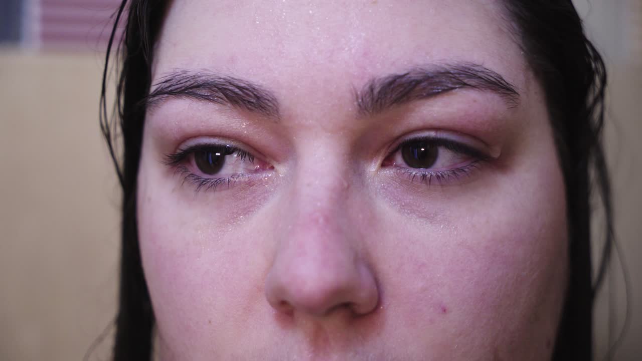 mirada cruda de mujer con agua en la cara mirando a la cámara mira hacia otro lado, primer plano