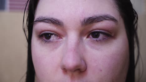 raw stare from woman with water on face looking at camera looks away, closeup