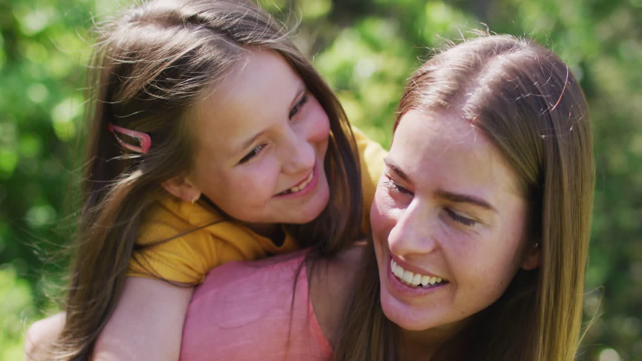 Retrato de madre caucásica llevando a su hija a la espalda en el jardín
