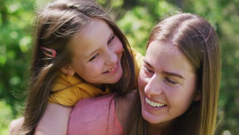 Porträt-Einer-Kaukasischen-Mutter,-Die-Ihre-Tochter-Auf-Dem-Rücken-Im-Garten-Trägt