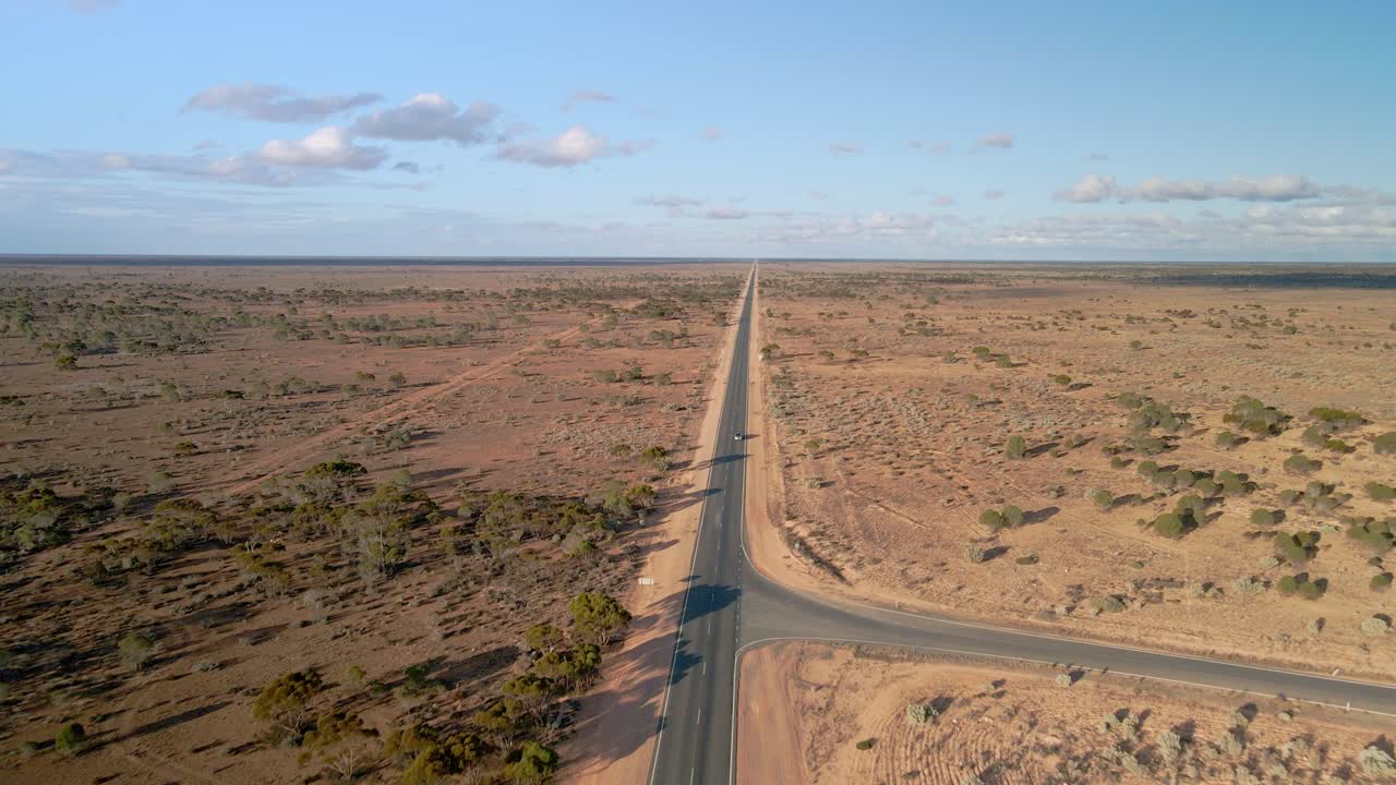 Aerial view above of cars driving on 90mile straight road, australia on a sunny, desert outback - pull back, drone shot