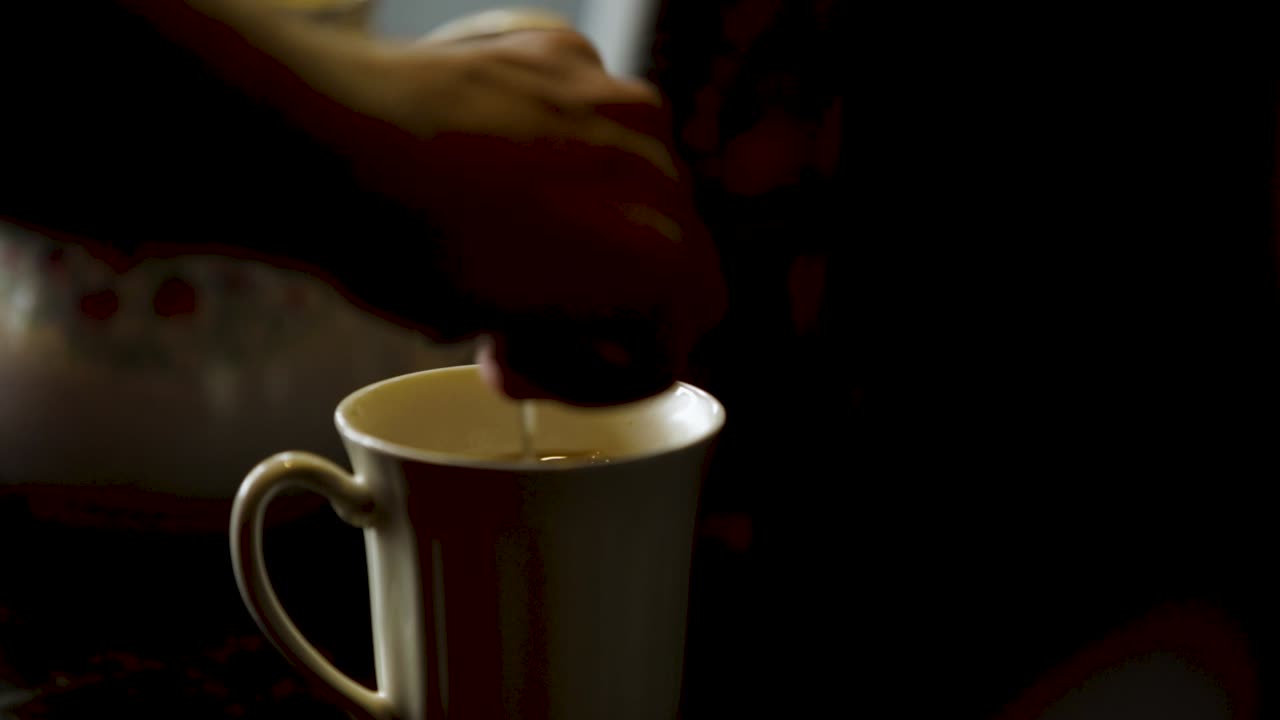 Spoon inserted into a coffee cup stirred and removed