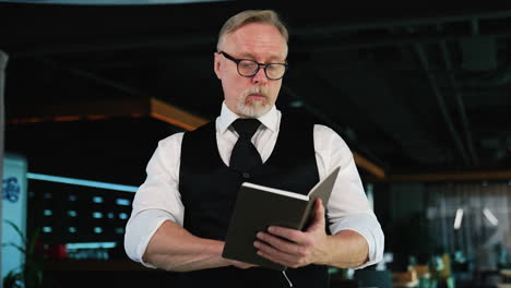 adult male businessman turning the pages of his paper notebook. man checks the information in his diary. low angle view.