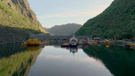 norwegian car ferry docked at industrial harbor for reparations, flat calm water in fjord, aerial